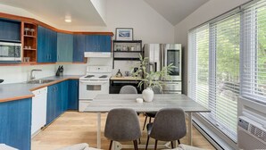 Una cocina moderna con armarios azules, una estufa blanca y una zona de comedor con dos sillas y una mesa.