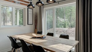 Un comedor con mesa de madera, sillas negras e iluminación colgante.