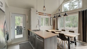 Una cocina moderna con una isla central, electrodomésticos de acero inoxidable y una zona de comedor con una mesa y sillas de madera.