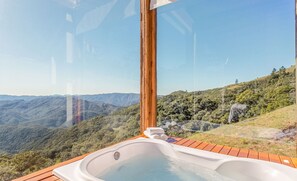 A hot tub with a wooden deck, overlooking a mountainous landscape. - Cabana acolhedora c jacuzzi serra VST015 (Anitápolis)
