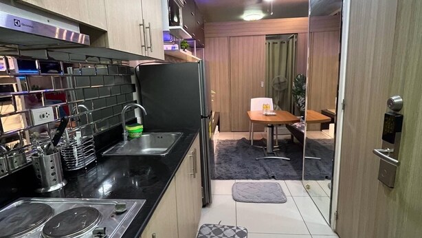 Una cocina funcional con encimera negra, electrodomésticos de acero inoxidable y armarios de madera.
