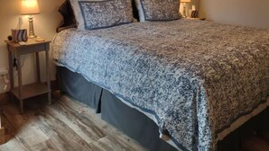 Un dormitorio con una cama grande, dos lámparas de noche, un arreglo en la pared y un cuadro.