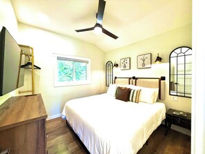 Une chambre à coucher avec un lit, une commode, une fenêtre et un ventilateur de plafond.