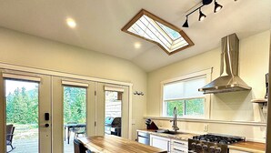Una cocina moderna con una isla de madera, electrodomésticos de acero inoxidable y ventanas amplias.
