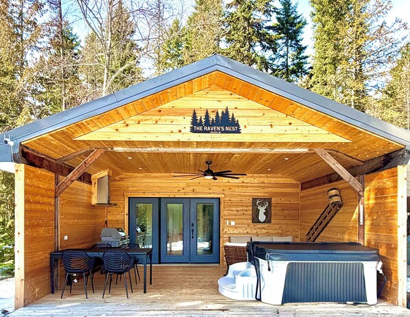Une cabane en bois dotée d’un patio couvert, d’un coin repas et d’un jacuzzi.