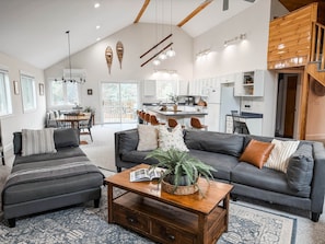 A spacious living area with a dark gray sofa, a wooden coffee table, and a dining area with a wooden table and chairs.