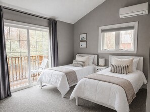 Une chambre avec deux lits, un balcon et un appareil de climatisation.