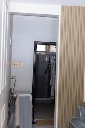 A narrow hallway with a radiator, a shower area, and a door leading to a room with a bed. - Lovely apartment with WiFi in vibrant Kampala with a cozy and calm environment. (Kampala)
