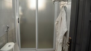 A bathroom with a glass shower enclosure, a toilet, and a towel rack with towels. - Lovely apartment with WiFi in vibrant Kampala with a cozy and calm environment. (Kampala)
