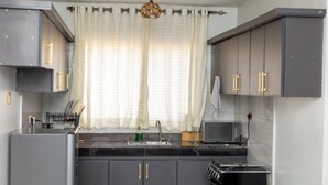 A kitchen with grey cabinets, a microwave, a sink, and a stove. - Lovely apartment with WiFi in vibrant Kampala with a cozy and calm environment. (Kampala)