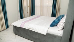 A bedroom with a bed, curtains, and a view through the window. - Lovely apartment with WiFi in vibrant Kampala with a cozy and calm environment. (Kampala)