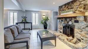 Ein Wohnzimmer mit Kamin aus Stein, einer Couch, einem Couchtisch und einem Essbereich mit Tisch und Stühlen.