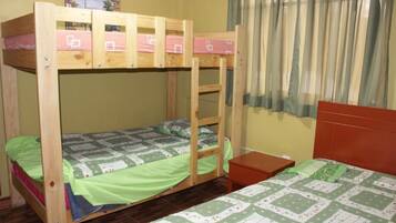 A bunk bed room with a ladder, a small table, and a window with curtains.