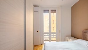 A bedroom with a bed, a nightstand, and a door leading to a balcony. - Easy Rome-ing (Roma)
