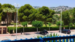 A parking area with cars, trees, and a distant view of a town. - SPECTACULAR APARTMENT IN FIRST LINE OF THE BEACH (Moraira)