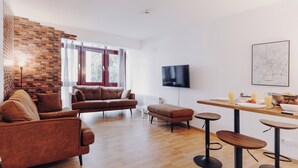 A modern living room with a brick wall, a sofa, a coffee table, and a TV mounted on the wall. - A time-out in the city center (Osnabrück)