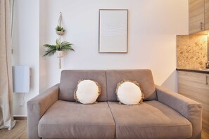 A modern living room with a grey sofa, two decorative pillows, a wall-mounted plant, and a framed artwork. - "cozy Apartment 1bdr/4p - Paris 8th/saint-lazare (Paris)
