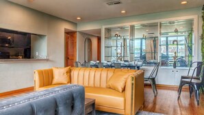 A modern living room with a leather sofa, a blue armchair, and a dining area with a glass table and chairs. - C Houston Resort Style Heated Pool (Houston)