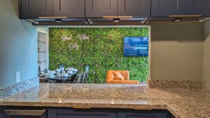 A kitchen with a granite countertop, a TV mounted on the wall, and a green wall with a 'Good Vibes Only' sign. - C Houston Resort Style Heated Pool (Houston)