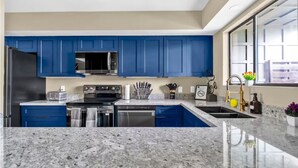 A modern kitchen with blue cabinets, stainless steel appliances, and granite countertops. - C Houston Resort Style Heated Pool (Houston)
