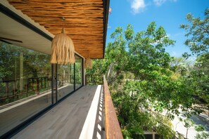 A wooden deck with glass railings overlooking a lush green landscape. - PH Exclusivo Alberca y Terraza  (Tulum)