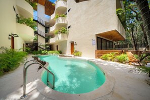 A modern hotel with a central swimming pool, multiple balconies with plants, and a wooden deck area. - PH Exclusivo Alberca y Terraza  (Tulum)