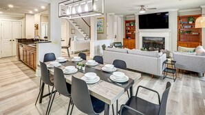 Una cocina moderna con comedor, una sala de estar con chimenea y una escalera que sube a otro nivel.