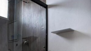 Ein modernes Badezimmer mit einer Glasdusche, einer Toilette und einer kleinen Ablagefläche.