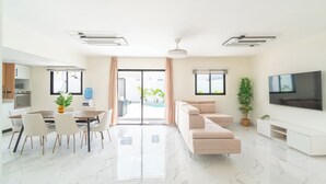 Un salon moderne comprenant un canapé, un téléviseur et un coin repas avec des chaises et une table.