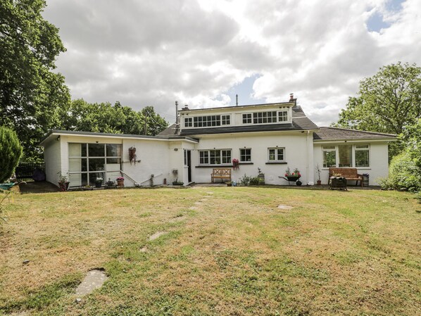 A two-story white house with a front porch, a small garden, and a lawn.