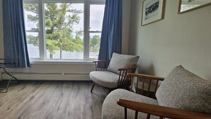 A room with a large window, a drying rack, two upholstered chairs, and a framed picture on the wall. - Juniper Motel-King Studio*RM2*Pet Friendly*Lakefront*ATV Access (Greenville)