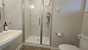 Un bagno con doccia vetro, lavandino bianco e rubinetteria cromata, e un water.