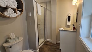 A bathroom with a toilet, a shower, a sink, and a towel rack. - Juniper Motel-Double Queen-RM4-Pet Friendly*ATV Access*Lakefront (Greenville)