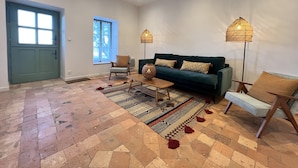 A spacious living room with a green sofa, a patterned rug, and two floor lamps. - Historic Comfort in the Heart of Ballon (Ballon-Saint-Mars)