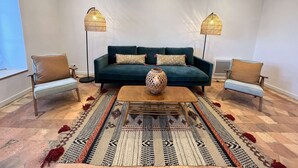 A living room with a teal sofa, two armchairs, a coffee table, and two floor lamps. - Historic Comfort in the Heart of Ballon (Ballon-Saint-Mars)