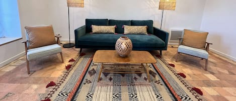 Una sala de estar con un sofá color turquesa, dos sillones, una mesa de centro y dos lámparas de pie.