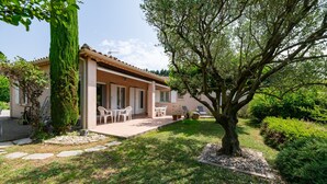 A house with a patio, outdoor seating, and a tree.