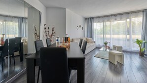 Ein modernes Wohnzimmer mit Essbereich, großen Fenstern und einem Topf mit Pflanze.