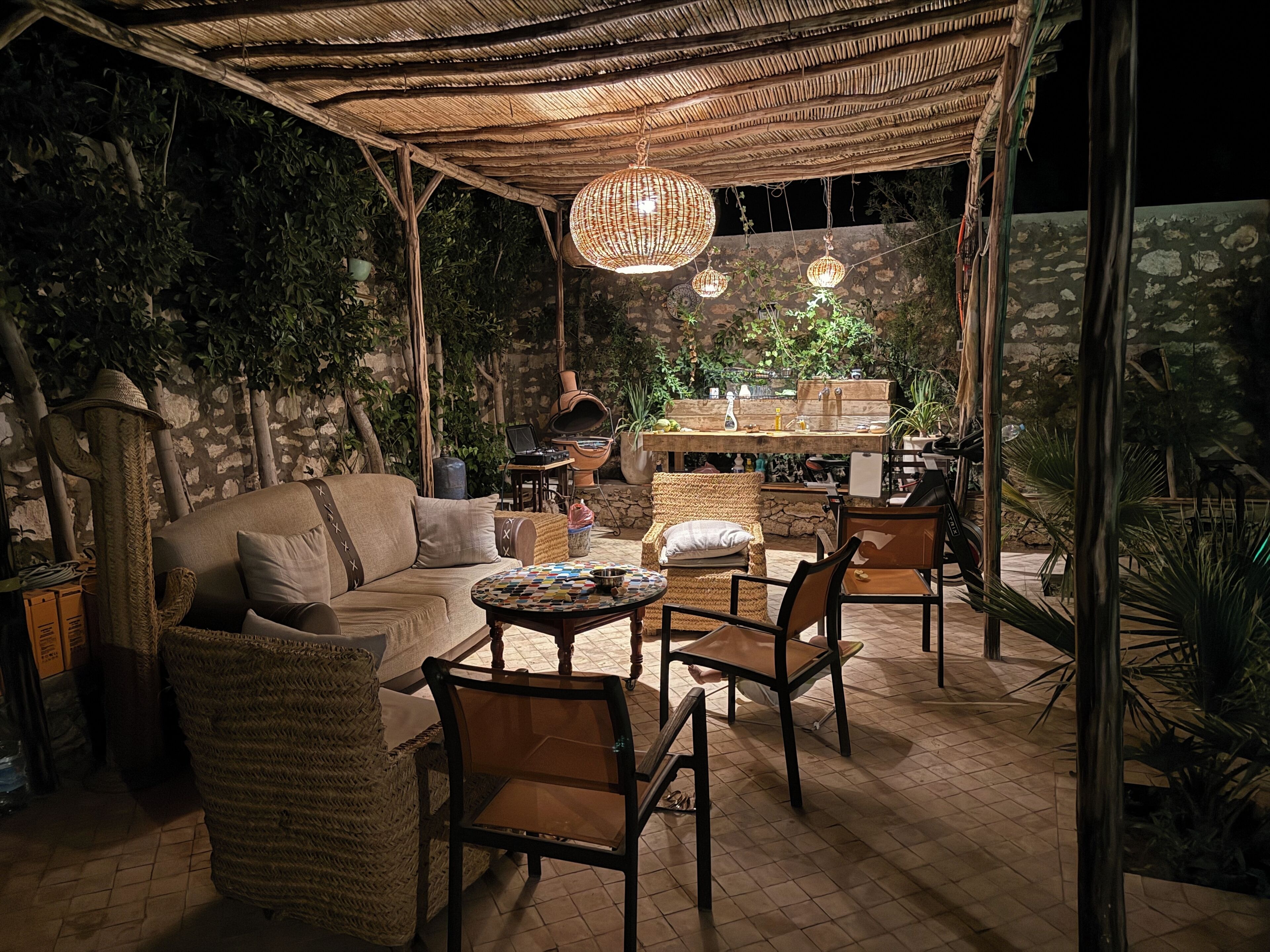 An outdoor patio area with a sofa, chairs, a table, and a hanging light fixture.