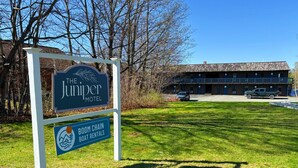 A motel sign with a boathouse and a building in the background.