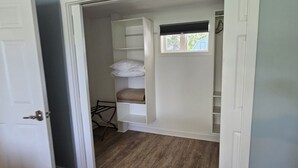 A walk-in closet with shelves, a hanging rack, and a window.