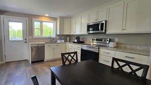 A compact kitchen with white cabinets, a microwave, an oven, and a dishwasher.