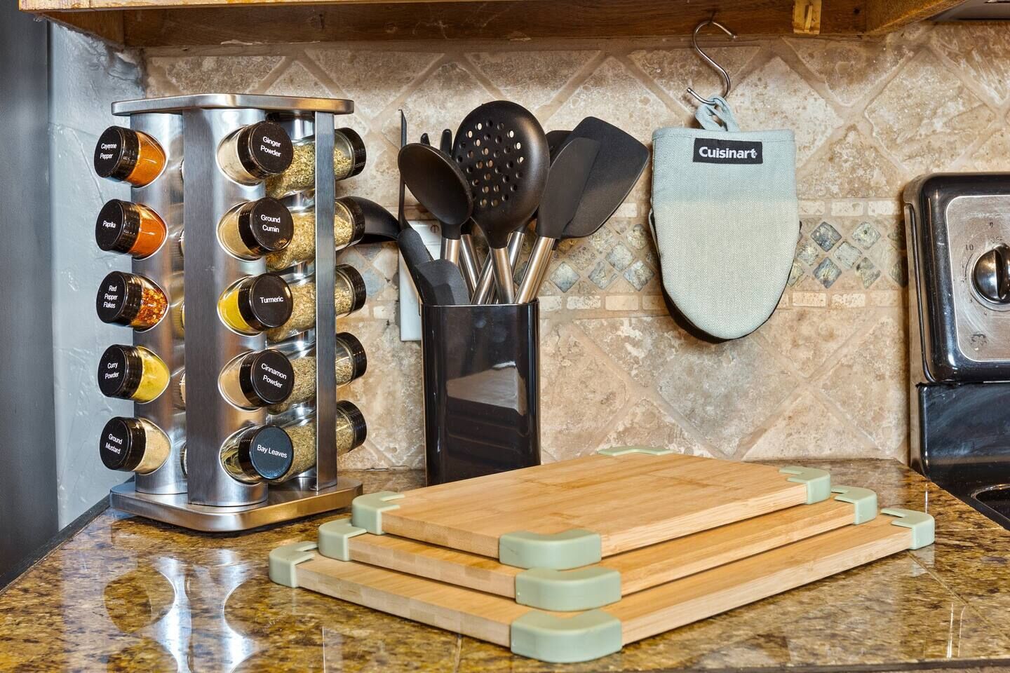 Une cuisine équipée d’un étagère à épices, d’une planche à découper en bois et d’un porte-ustensiles suspendu.