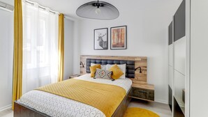 Una camera da letto moderna con un letto, un comodino, una lampada da comodino, un armadio e un lampadario.