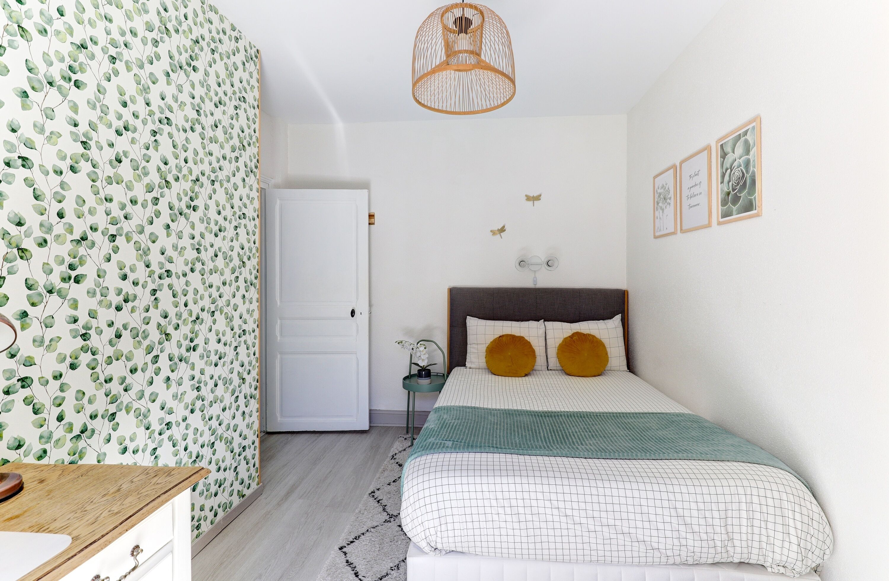 Ein Schlafzimmer mit Bett, Nachttisch, Lampe und einer Tür.