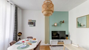Un soggiorno moderno con angolo da pranzo, televisione e libreria.