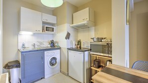 A compact kitchen with a washing machine, microwave, and a small refrigerator.