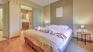 A hotel room with a large bed, a bedside table with a lamp, a wardrobe, and a mirror.