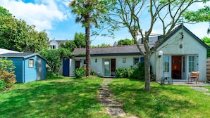 A house with a stone pathway leading to the front door, surrounded by a well-maintained lawn and a small shed.