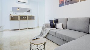Una sala de estar moderna con un sofá gris, una mesita redonda y un mueble con puertas de vidrio.